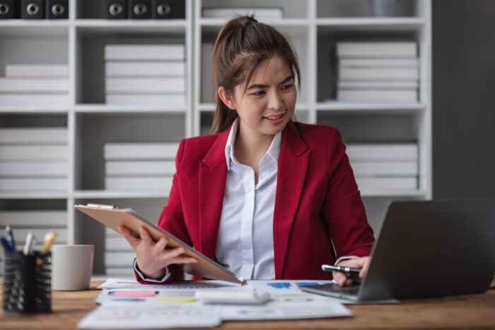 Person exploring investment trusts at their desk with clipboard and laptop